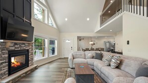 A spacious living area with a fireplace, a sectional sofa, and a dining area in the background. - The South Harmony House, Luxury Escape, HotTub, 5,000sqft, Gameroom (Lake Harmony)