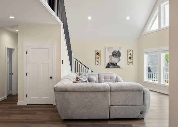 A modern living room with a sectional sofa, a staircase, and artwork on the walls. - The South Harmony House, Luxury Escape, HotTub, 5,000sqft, Gameroom (Lake Harmony)