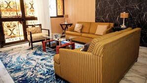 A living room with a sofa, armchair, coffee table, and patterned rug. - Clos D'or appartement (Douala)