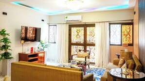 A living room with a sofa, armchair, TV, and decorative items. - Clos D'or appartement (Douala)