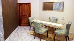A dining area with a glass table, patterned chairs, a wooden door, and a marble floor. - Clos D'or appartement (Douala)