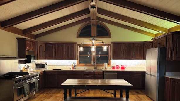 A kitchen with wooden cabinets, a large island, a stove, and a refrigerator. - Dublin's Private Ranch Retreat (Delaware)