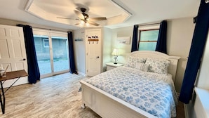 A bedroom with a bed, a nightstand, a ceiling fan, a door, and a view of the outside. - Dublin's Private Ranch Retreat (Delaware)
