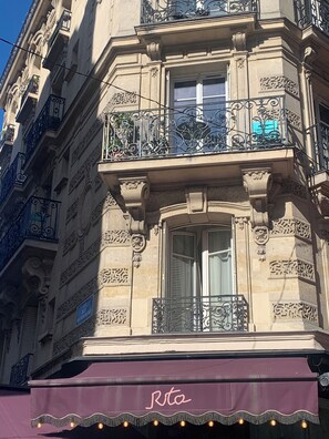 Ein Gebäude mit aufwendiger Architektur, einem Balkon mit schmiedeeisernen Geländern und einem Schild mit dem Namen 'Rta' am Vordach.