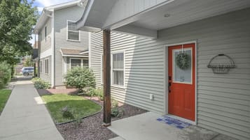 A residential building with a red door, a welcome mat, and a number '5' sign.