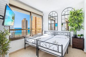 A bedroom with a bed, a TV, a window with a view of the sea, and a potted plant. - Las Rocas 14-A Apartment Levante Beach (Benidorm)