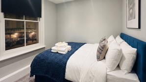 Ein Schlafzimmer mit einem Bett, einem Fenster und einem an der Wand hängenden Bild.