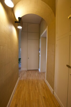 A hallway with wooden flooring, a white door, and a wall with a brick pattern. - Appartamento Nina Lungotevere Flaminio (Roma)