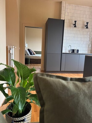 A modern living room with a sofa, a potted plant, and a view into a bedroom. - Appartamento Nina Lungotevere Flaminio (Roma)