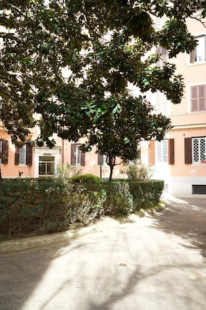 A building with a paved courtyard, a tree, and a hedge. - Appartamento Nina Lungotevere Flaminio (Roma)