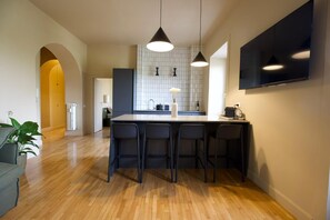 A modern kitchen with a central island, bar stools, pendant lighting, and a tiled backsplash. - Appartamento Nina Lungotevere Flaminio (Roma)