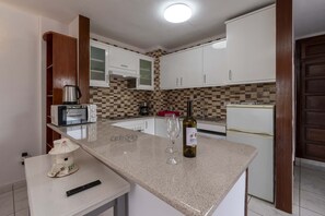 A kitchen with white cabinets, a microwave, a coffee maker, and a wine bottle on the counter. - San Marino Studio 8 (Los Cristianos)