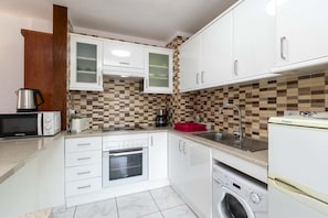 A compact kitchen with white cabinets, a microwave, a coffee maker, a sink, and a washing machine. - San Marino Studio 8 (Los Cristianos)