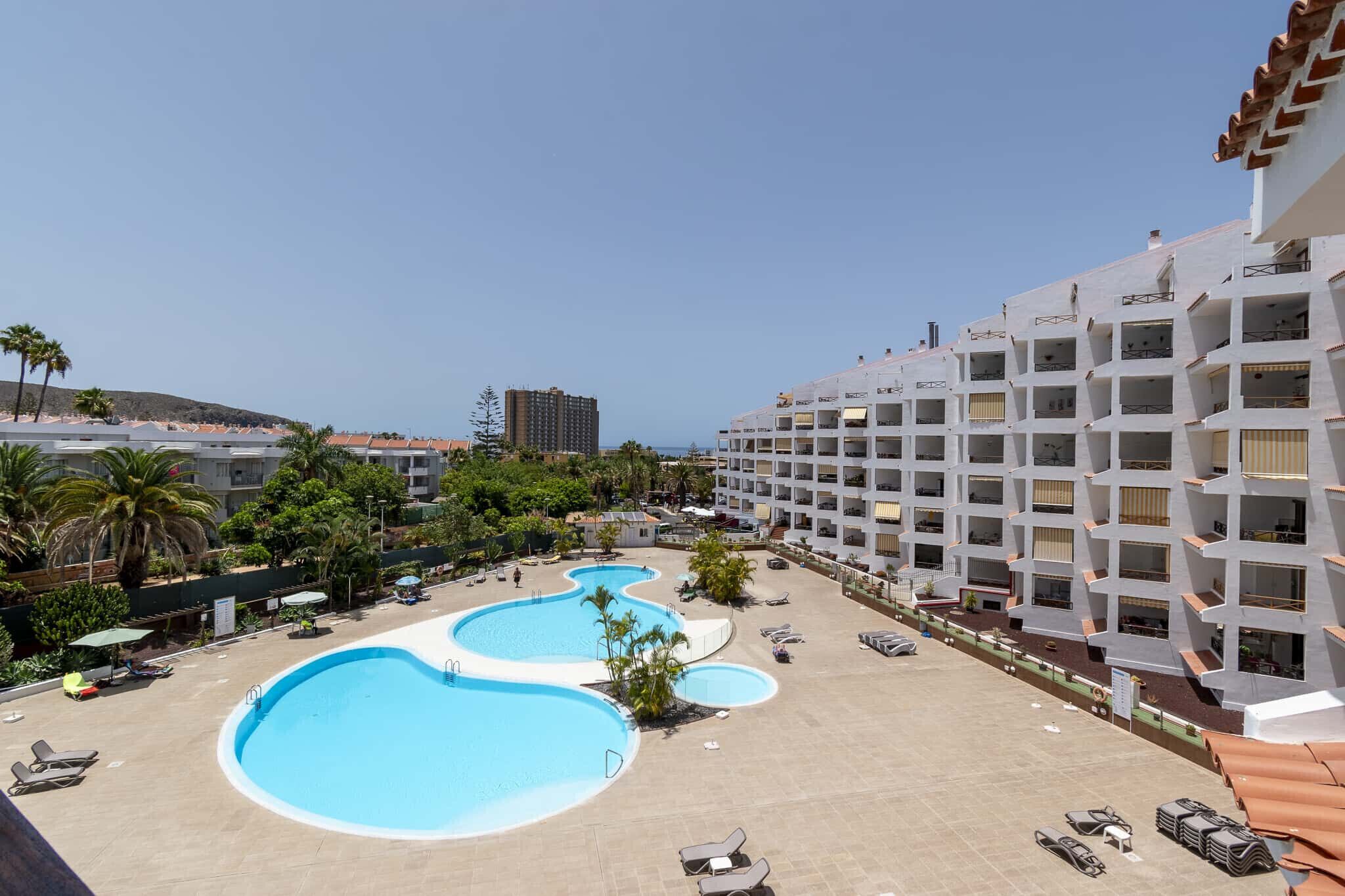 A hotel with multiple swimming pools, a beach area, and a view of the sea.