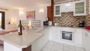 Uma cozinha moderna com armários brancos, micro-ondas, máquina de café e torradeira.
