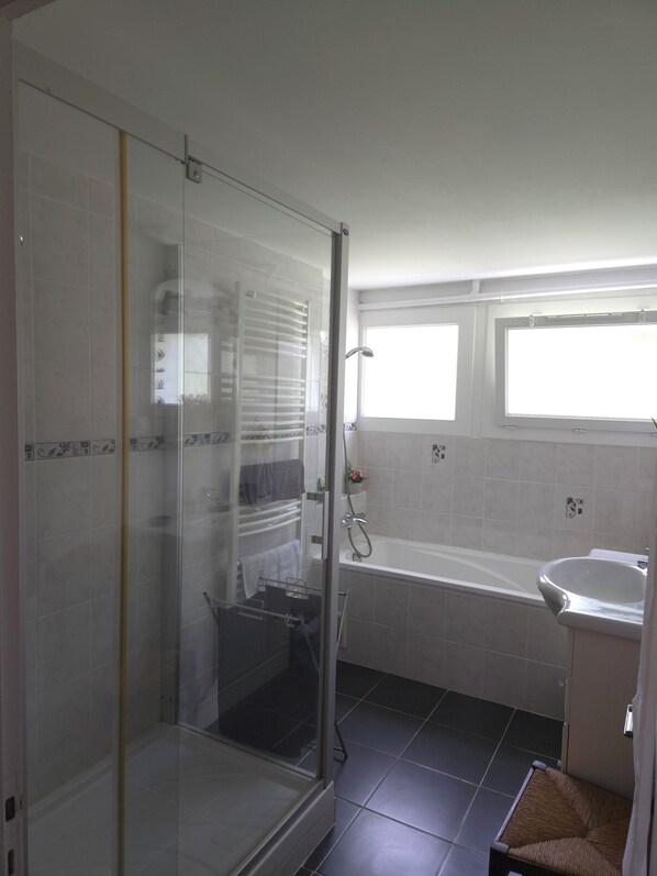 A bathroom with a glass-enclosed shower, a bathtub, and a sink.