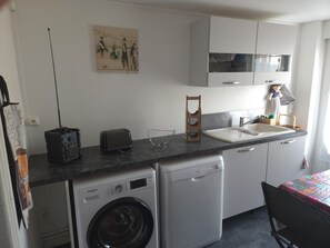 A compact kitchen with a washing machine, a toaster, a sink, and a microwave.