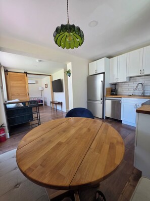 Eine moderne Küche mit weißen Schränken, einem Edelstahlkühlschrank und einem Holztisch.