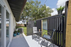 Eine Terrasse mit Tisch und Stühlen, einem Blumentopf und einem Holzzaun.