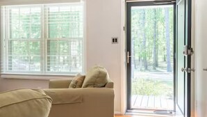 A room with a sofa, a large window, and a door leading outside. - The Park House I Family Retreat Near Fort Benning & Auburn (Columbus)
