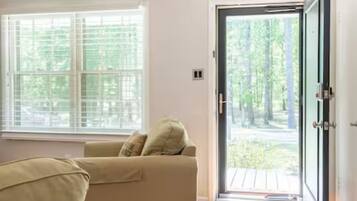 A room with a sofa, a large window, and a door leading outside.