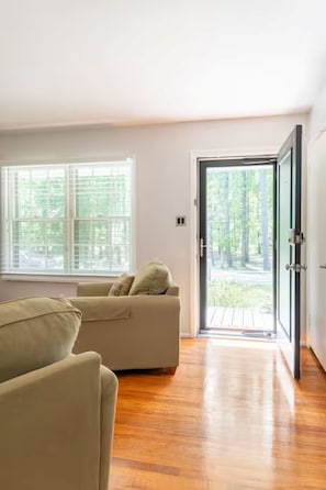 A room with a sofa, a large window, and a door leading outside. - The Park House I Family Retreat Near Fort Benning & Auburn (Columbus)