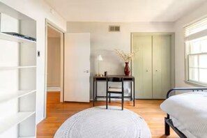 Une chambre à coucher avec un lit, un bureau avec une chaise, une fenêtre et une armoire.