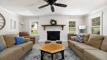 A living room with two sofas, a coffee table, a fireplace, and a ceiling fan.