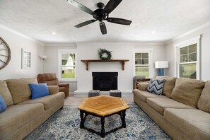 Ein Wohnzimmer mit zwei Sofas, einem Couchtisch, einem Kamin und einem Deckenventilator.
