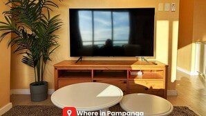 Una sala de estar con televisor, muebles de madera, una planta en maceta y una pequeña mesa.