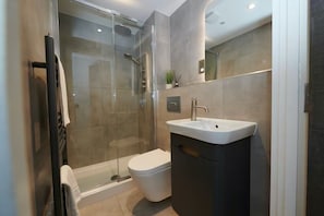 A modern bathroom with a glass-enclosed shower, a standalone toilet, and a built-in sink. -  2-Bed, 2-Bath Apartment in the Heart of York City Centre with secure parking (York)