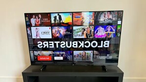 En platt-TV stående på ett svart stativ, med Netflix-gränssnittet synligt och olika program visas.