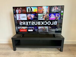 A flat-screen TV on a black stand with a Netflix interface displaying various shows. -  2-Bed, 2-Bath Apartment in the Heart of York City Centre with secure parking (York)