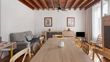Een ruime woonkamer met een houten eettafel, een bank en een televisie.