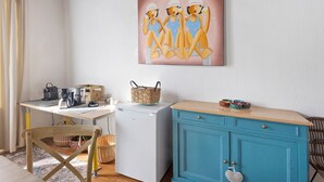 Een kleine keuken met een koffiezetapparaat, een koelkast en een blauwgroen kastje.