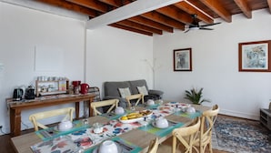 A dining area with a wooden table set for six, surrounded by wooden chairs.