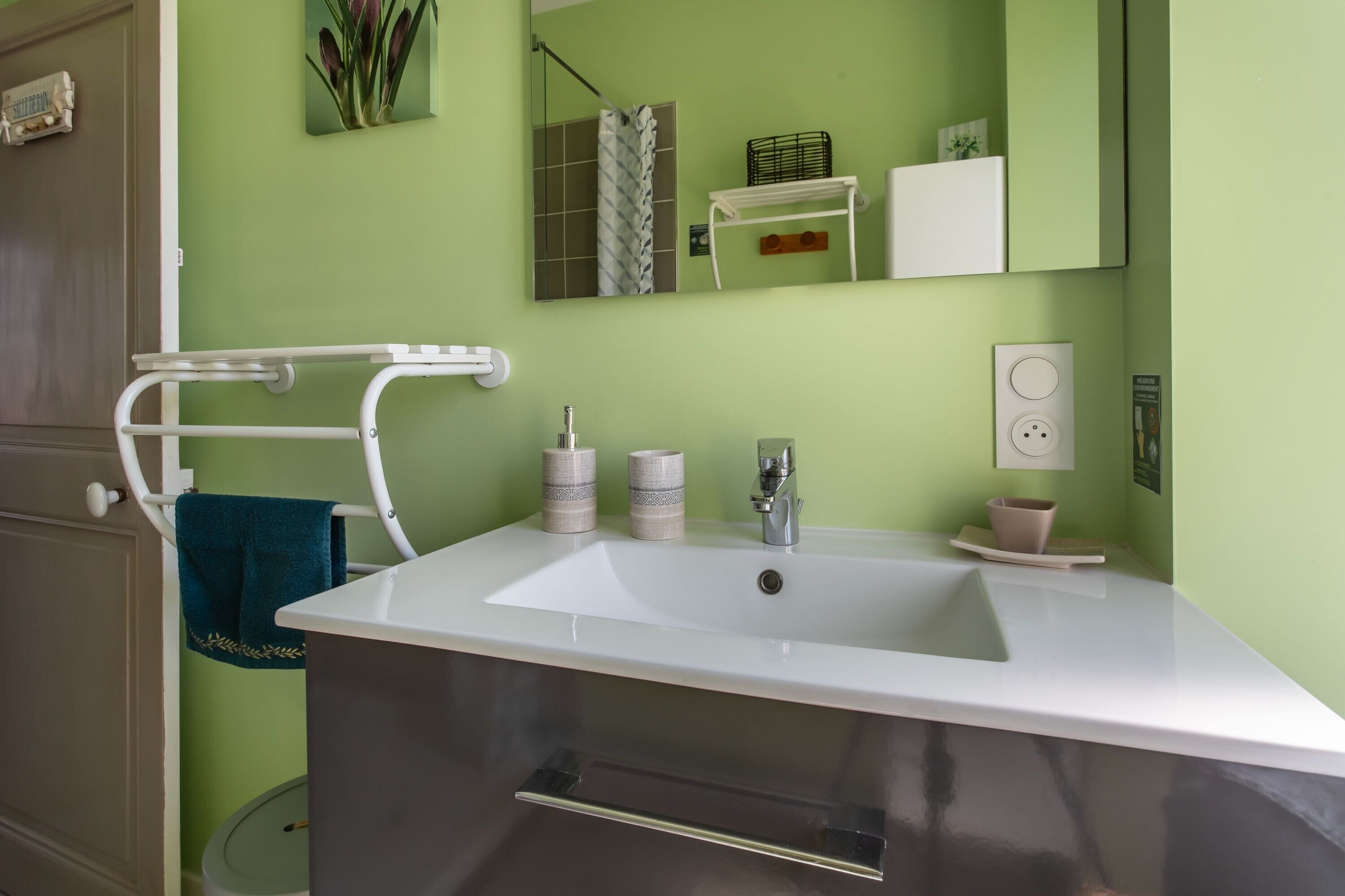 Une salle de bain avec un lavabo blanc, un porte-serviettes, un miroir et des toilettes.