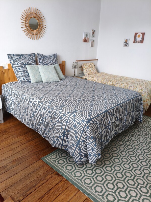 Een slaapkamer met een groot bed, een houten hoofdbord, een nachtkastje, een lamp en een spiegel aan de muur.
