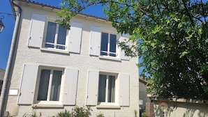 A two-story building with white exterior walls and shutters, a visible door, and a small sign with 'PRIVÉ' indicating private property.