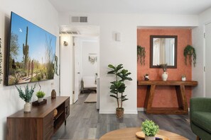 A modern living room with a flat-screen TV, a wooden coffee table, and a green sofa. - Stylish Tempe Stay ~ Swimming Pool, King Bed! (Tempe)