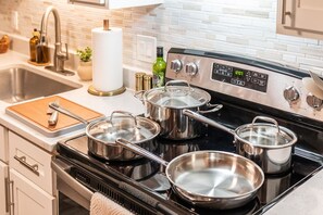 A kitchen with a stainless steel stove, pots, a wooden cutting board, and a sink. - Stylish Tempe Stay ~ Swimming Pool, King Bed! (Tempe)