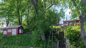 A dock with a wooden staircase leading to a red building with white trim. - Hay Bay Hytte - Waterfront Cottage (Greater Napanee)