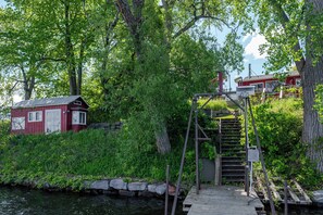 Eine Anlegestelle mit einer Holztreppe, die zu einem roten Gebäude mit weißen Verzierungen führt.