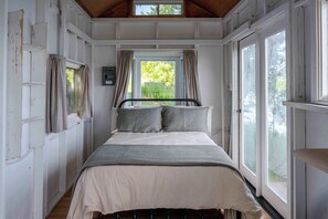 Ein Schlafzimmer mit Bett, Vorhängen, einem Fenster und einem Thermostat.