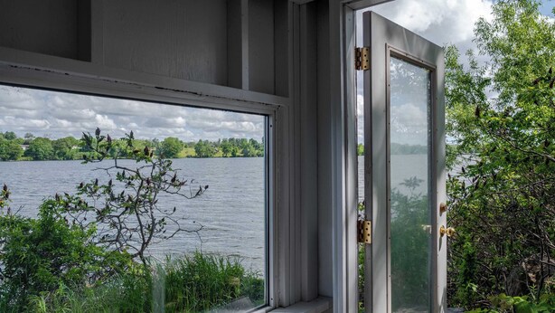A window with a view of a lake and surrounding greenery. - Hay Bay Hytte - Waterfront Cottage (Greater Napanee)
