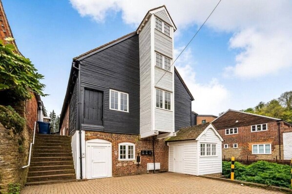 A two-story house with a steeply pitched roof, a white front door, and a brick exterior.