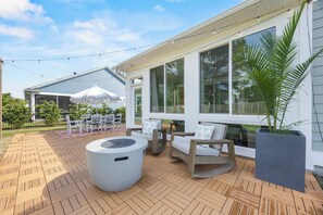 Une terrasse dotĂ©e dâun plancher en bois, de mobilier dâextĂ©rieur et dâune grande fenĂȘtre donnant sur la cour.