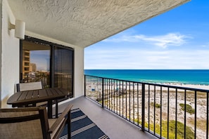 Ein Balkon mit Blick auf den Strand, einem Tisch und Stühlen.