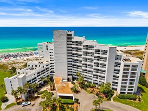 Ein Hochhaus-Hotel mit mehreren Balkonen, einem Dachgarten und Blick auf den Strand.