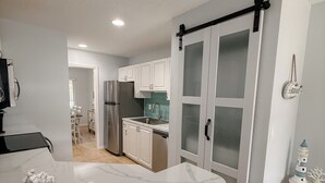 A modern kitchen with white cabinets, a marble countertop, and a sliding glass door. - Shorewalk 2BR/2BA Condo Minutes from Beach & IMG (Bradenton)